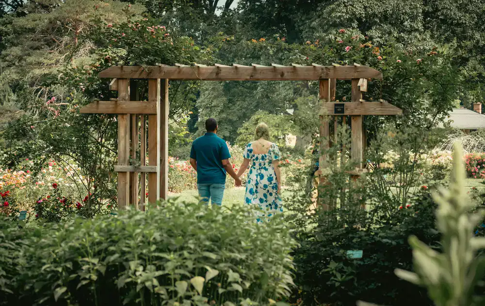 Couple holding hands under a lush floral arch