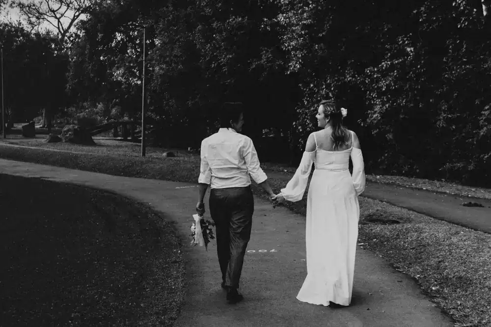 A joyful newlywed couple walking down a romantic, softly lit pathway